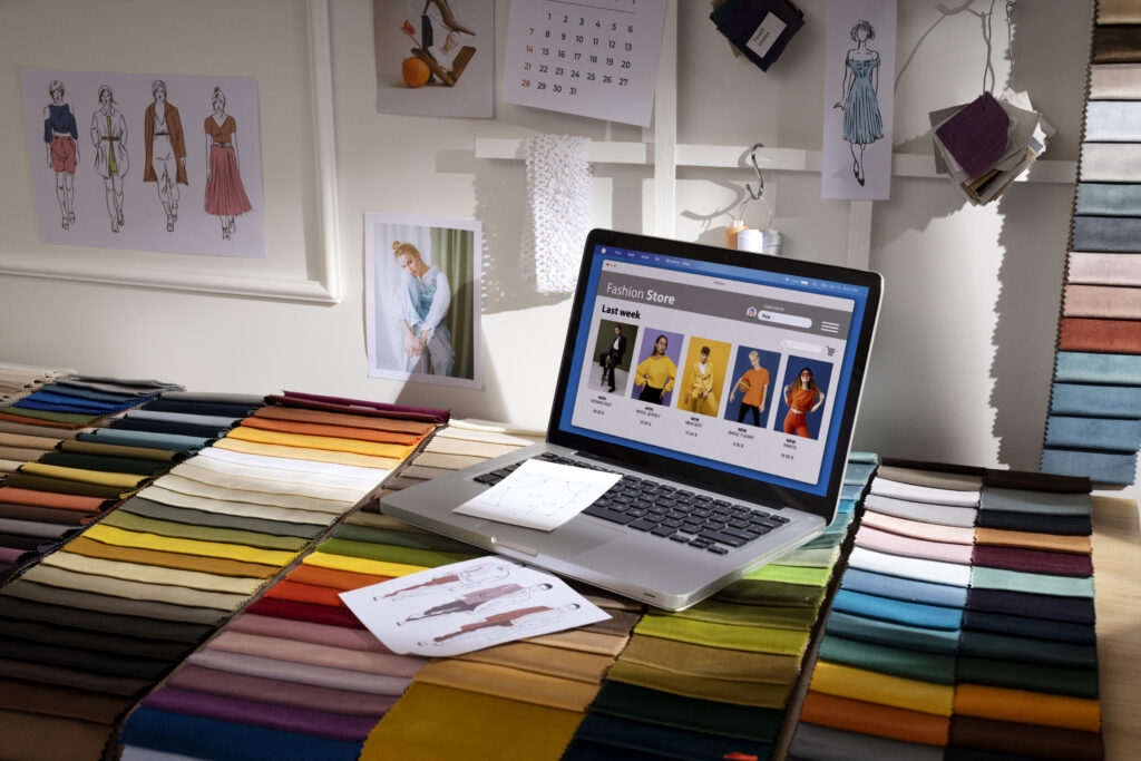 Laptop showing an online print-on-demand store with a table sticker, representing a creative workspace setup for digital entrepreneurs.
