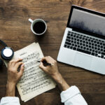 Aerial view of a laptop on a wooden table used for transcription services work setup