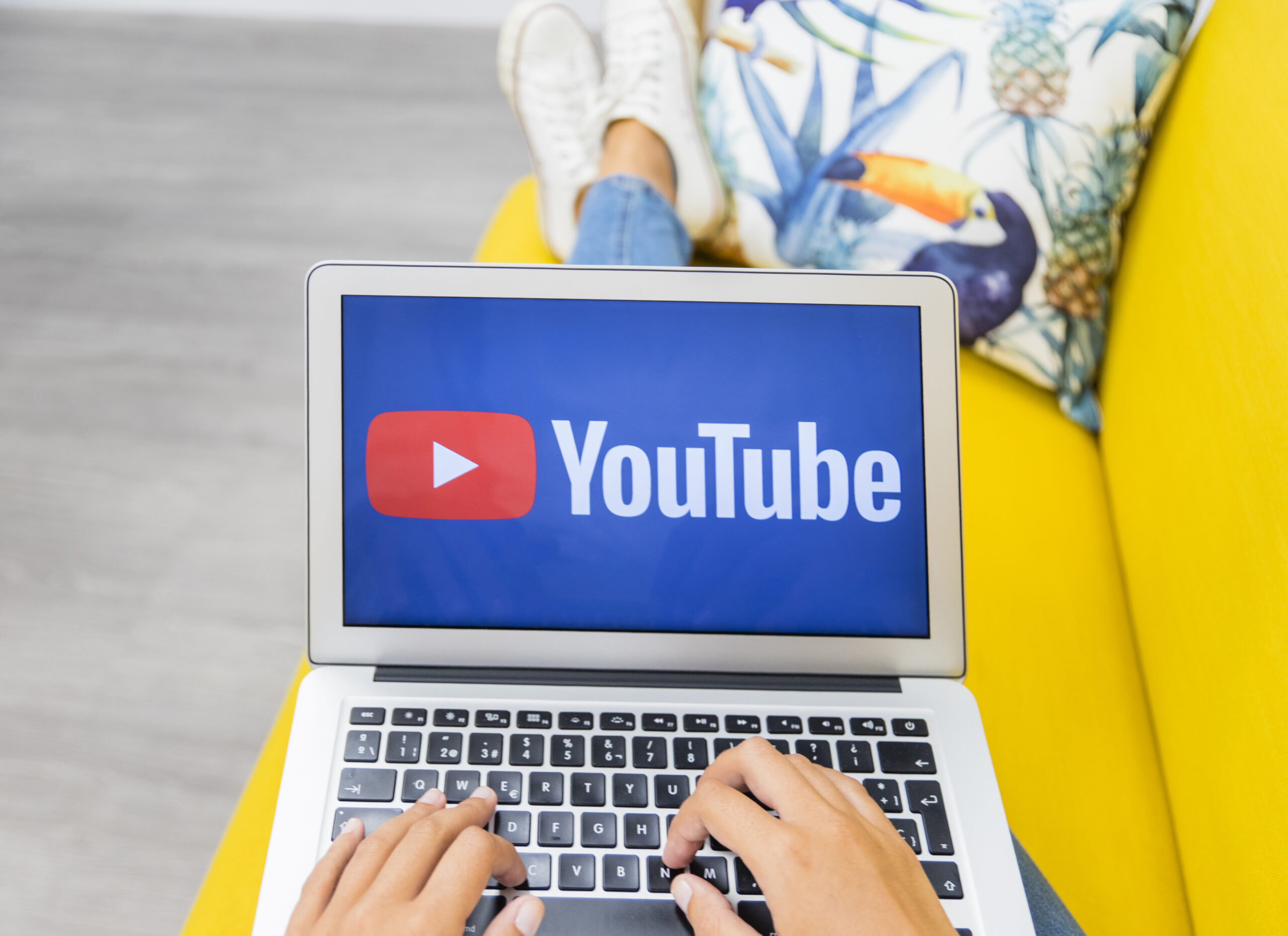 Female hands typing on laptop keyboard while working on a YouTube channel setup at home