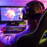 Side view of a focused gamer playing indoors with a headset and gaming setup