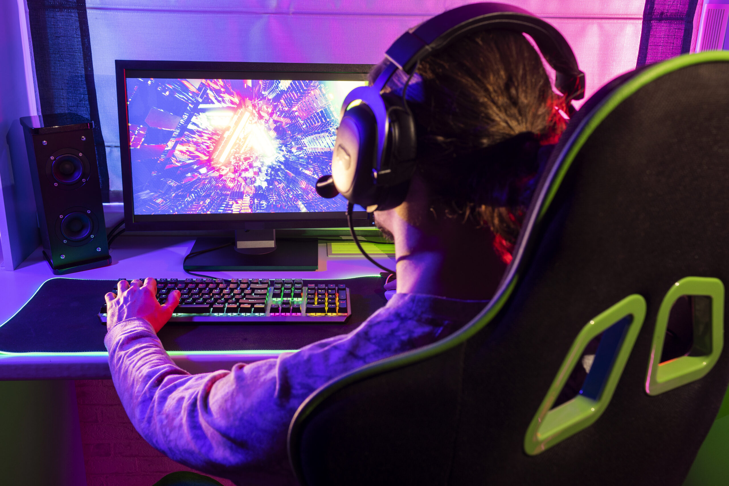 Side view of a focused gamer playing indoors with a headset and gaming setup