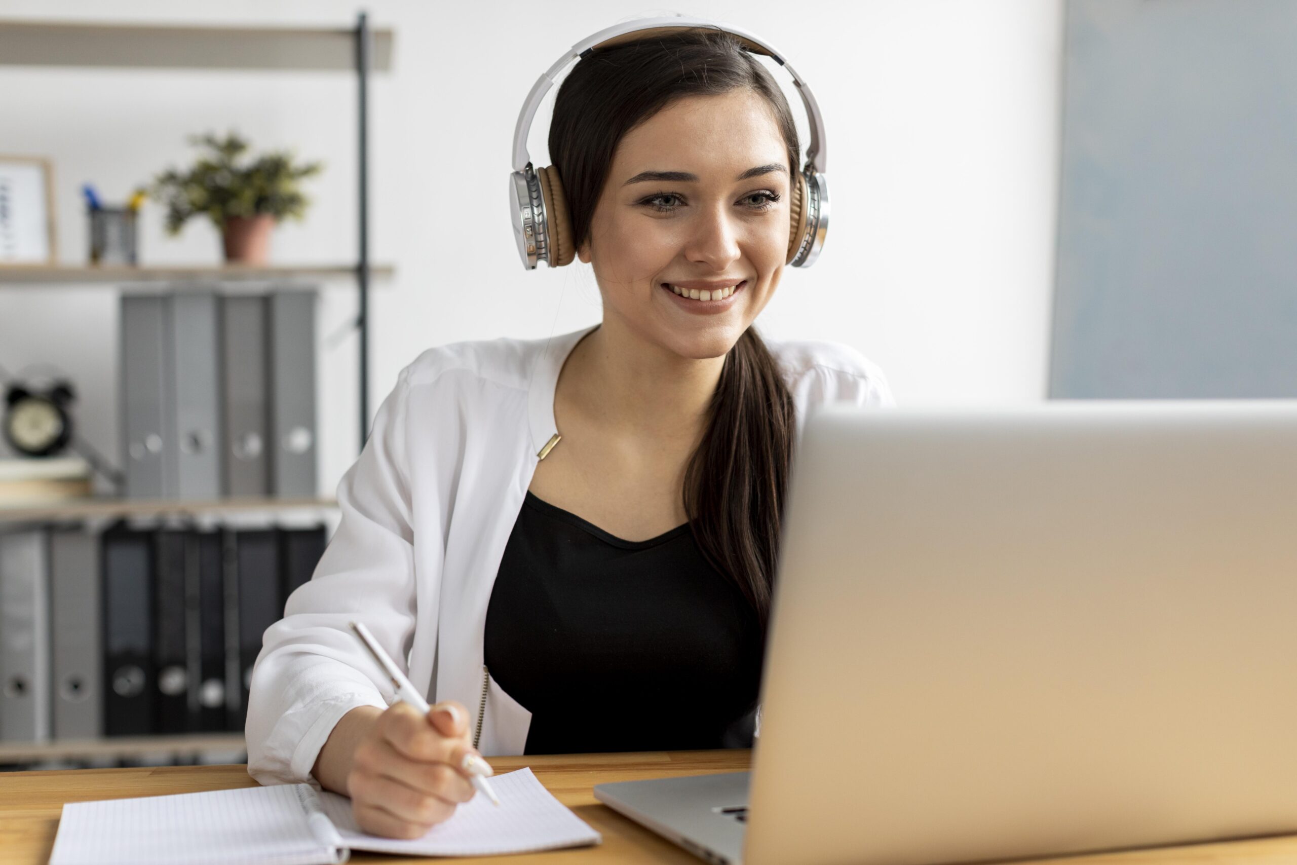 Freelance virtual assistant organizing client work on her laptop at a cozy remote workspace.