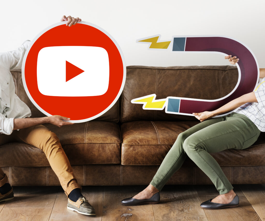 Group of diverse people holding a large YouTube icon symbolizing collaboration and starting a YouTube channel in 2025