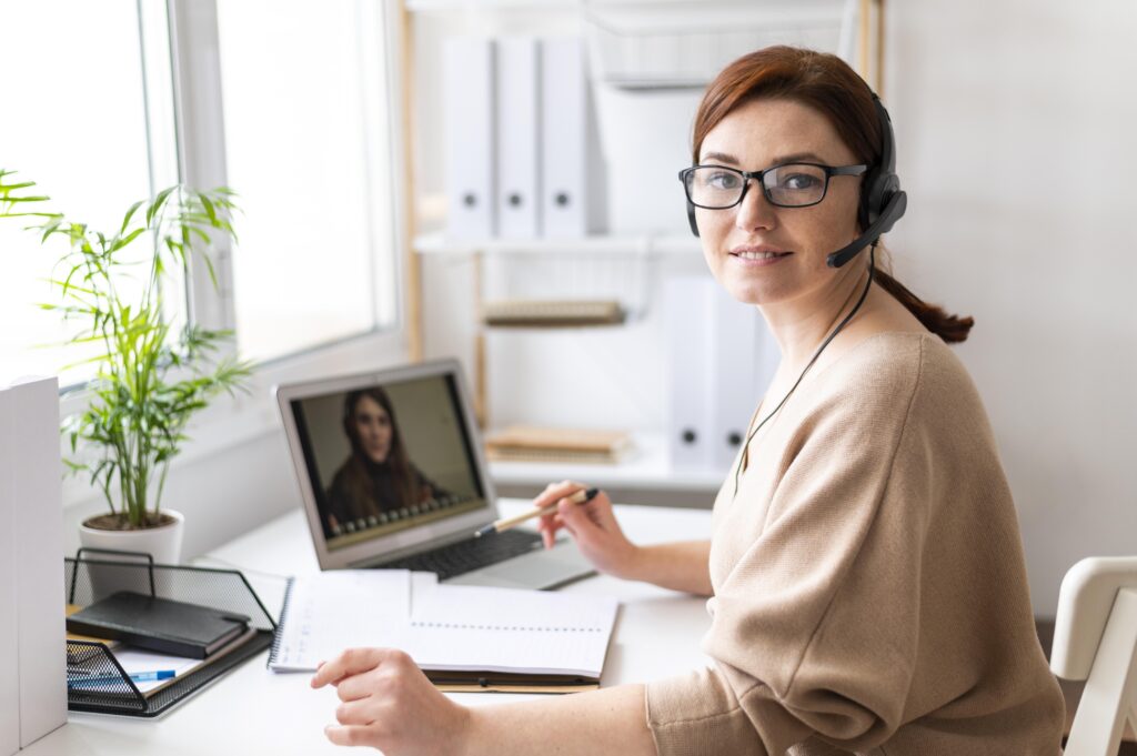 Young woman working from home as a virtual assistant, managing tasks on her laptop with headphones on.